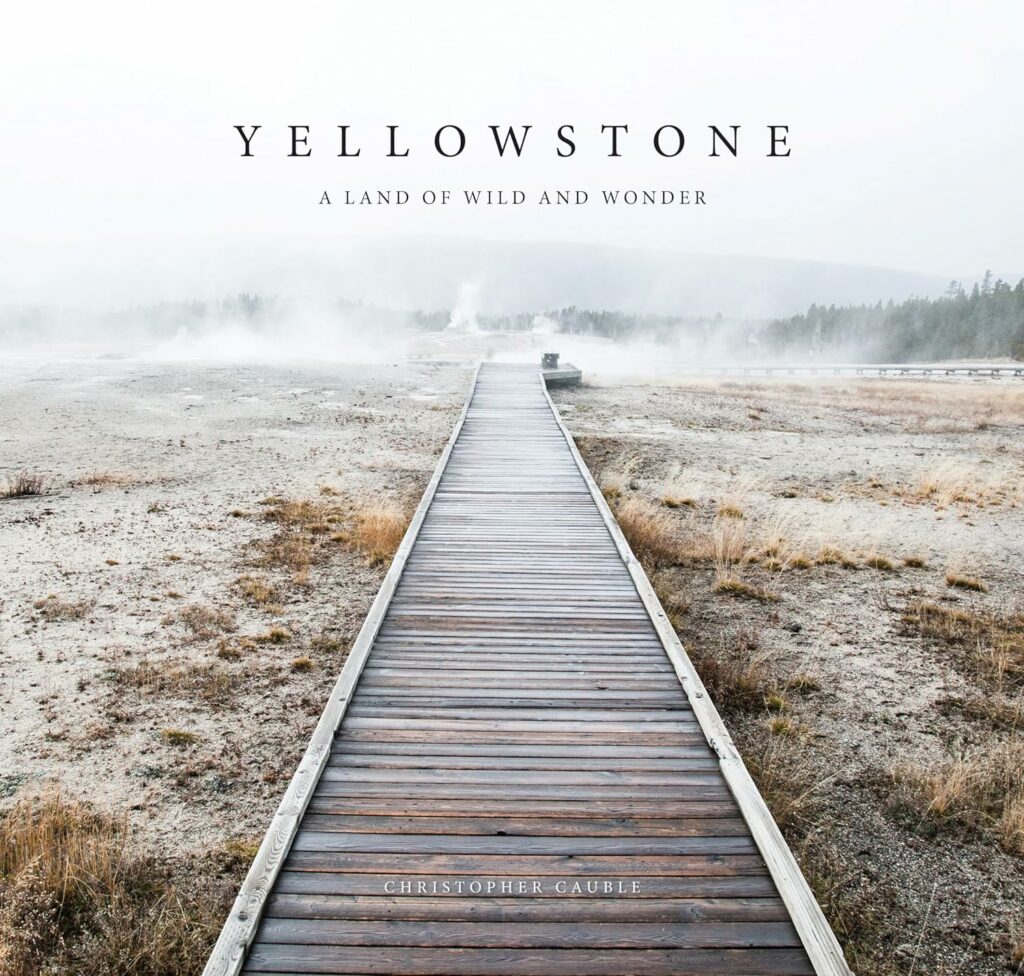 Yellowstone: A Land of Wild and Wonder" by Christopher Cauble: Alt text: "Photographic book 'Yellowstone: A Land of Wild and Wonder' showing a wooden boardwalk through geothermal areas, a visual treat for enthusiasts of Yellowstone Books.
