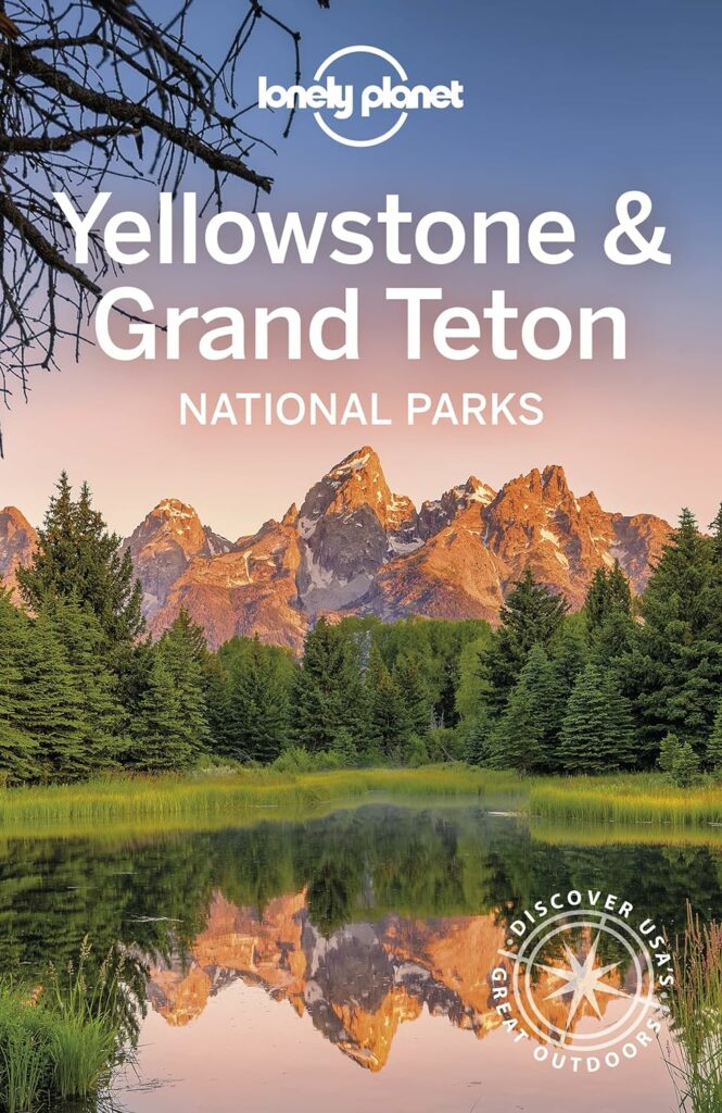 "Lonely Planet Yellowstone & Grand Teton National Parks": Alt text: "Travel guide 'Lonely Planet Yellowstone & Grand Teton National Parks' with stunning mountain reflections, an indispensable companion for Yellowstone Books travelers.