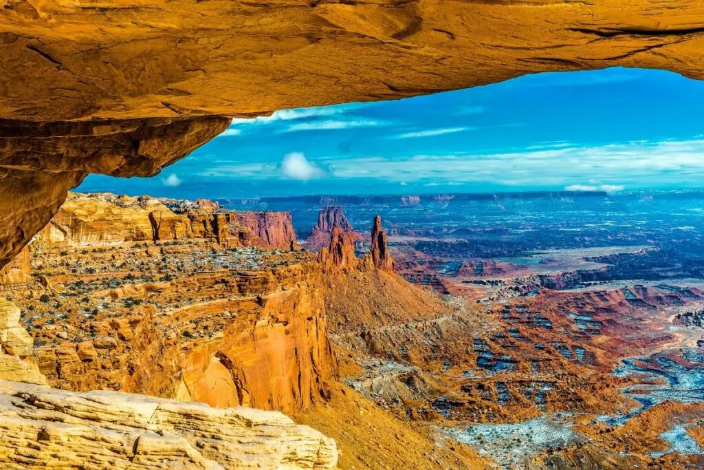 Looking through a rock arch ount across a canyon at sunrise.