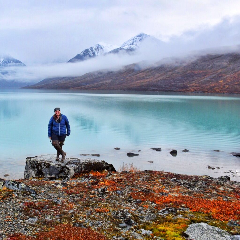 Jennifer (A woman) standing next to a turquoise blue lake in Alaska.