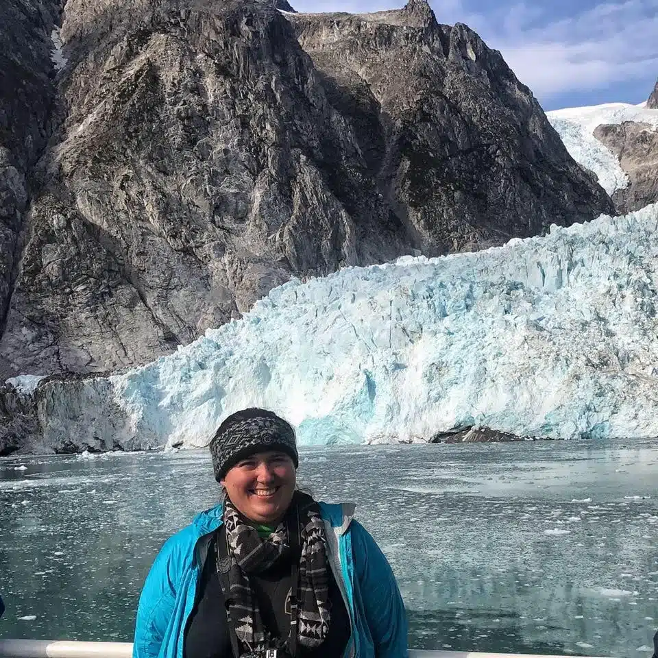 A woman standing on a boat near a glacier in Kenai Fjords National Park
