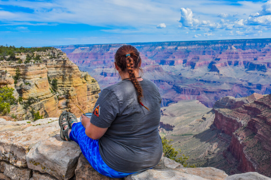 A women sitting down enjoying the view of the Grand Canyon. 