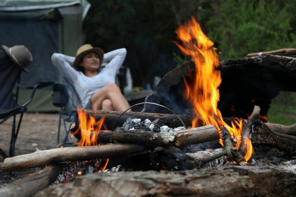 A women sitting by a campfire.