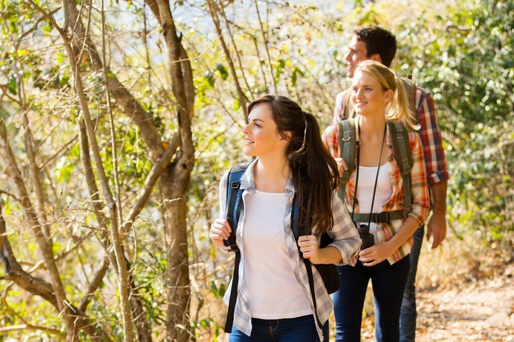 2 women and a men hiking in the woods.