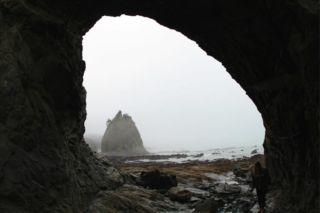 An image of a sea rock arch with a rock in the background. 