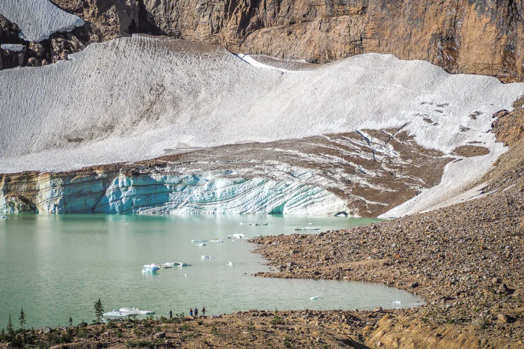 People standing near a glacier and glacier lake. 