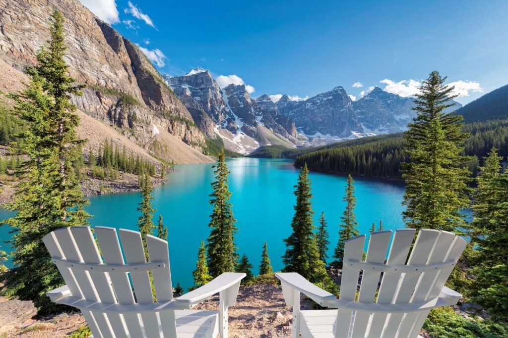 Two chairs in front of a blue mountain lake