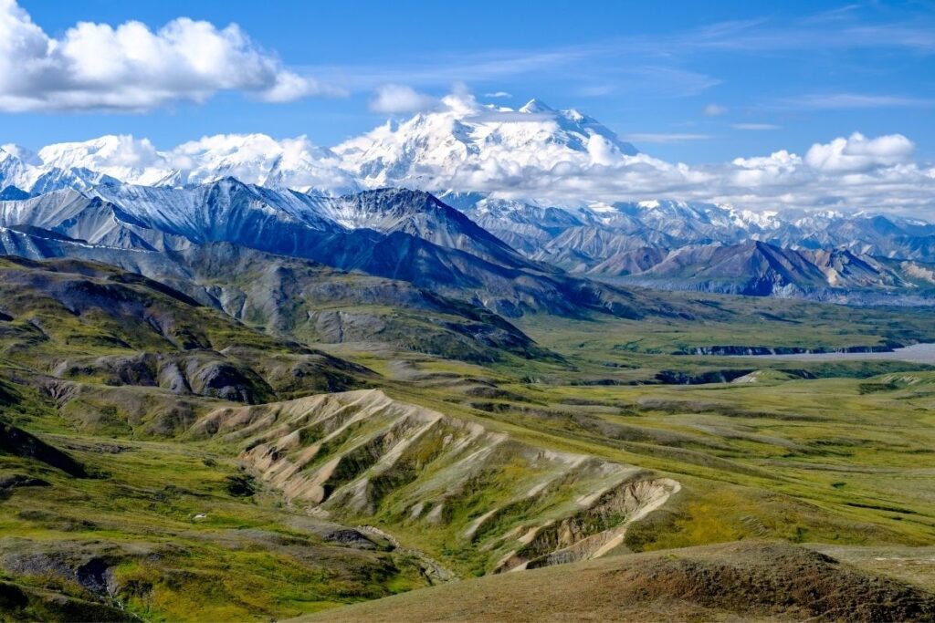 The green valleys in front of Denali which is partly hidden by the clouds.