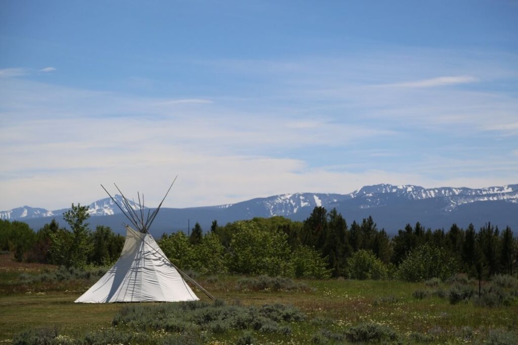 A teepee with mountains in the background.
