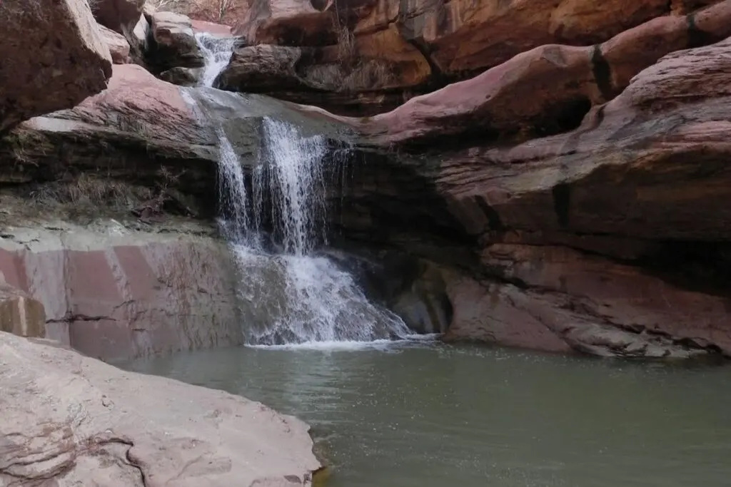 A waterfall spills over red rocks