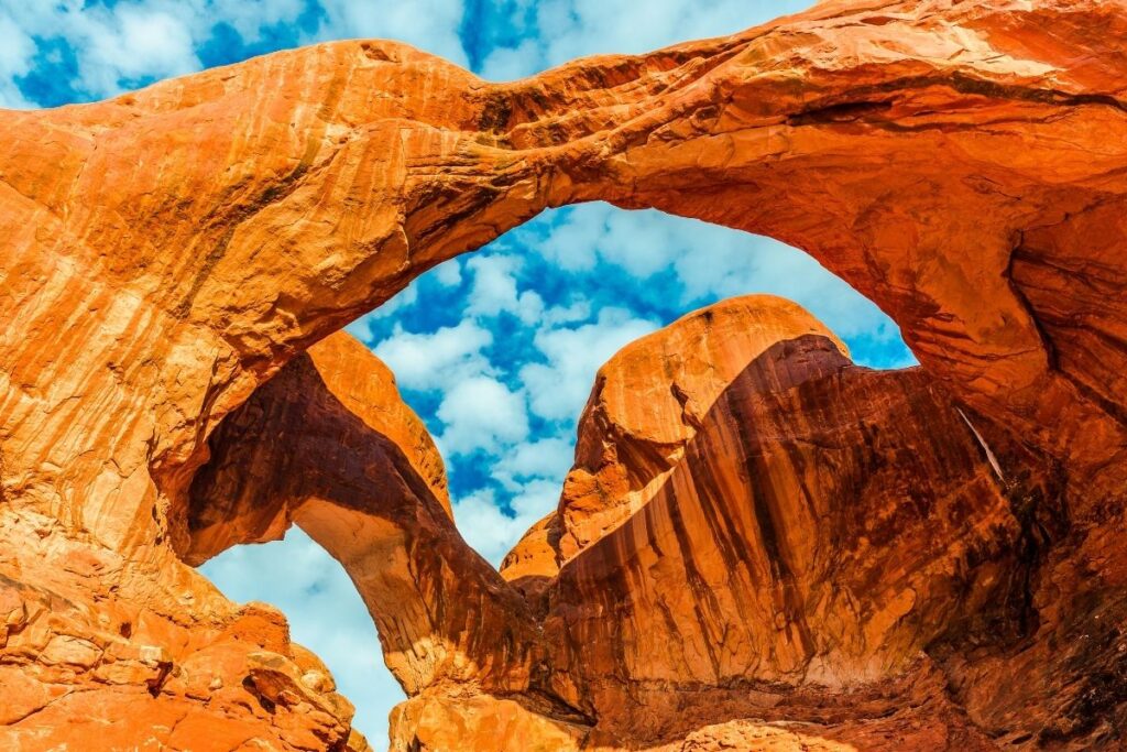 double orange rock arches with a cloudly blue sky