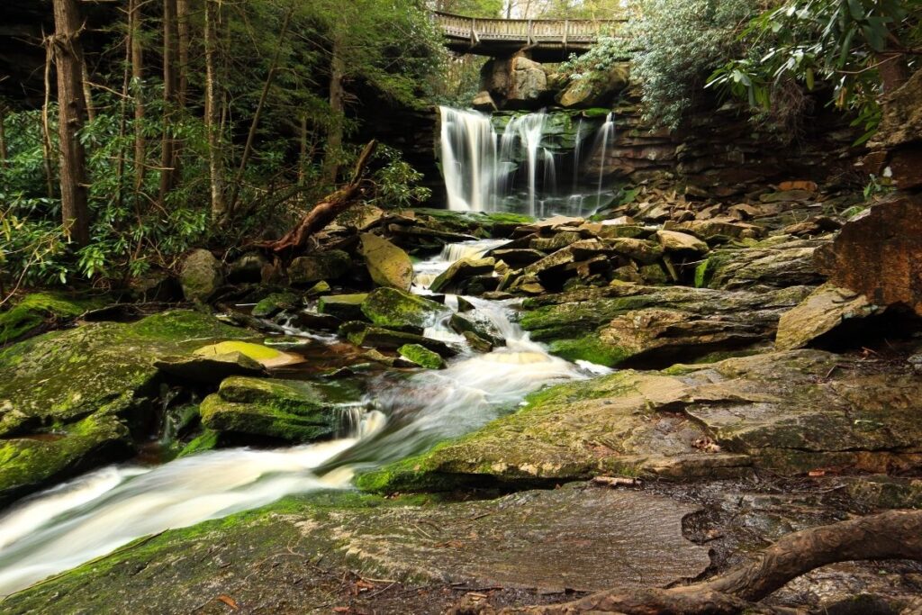 A rocky waterfall with a bridge in the background