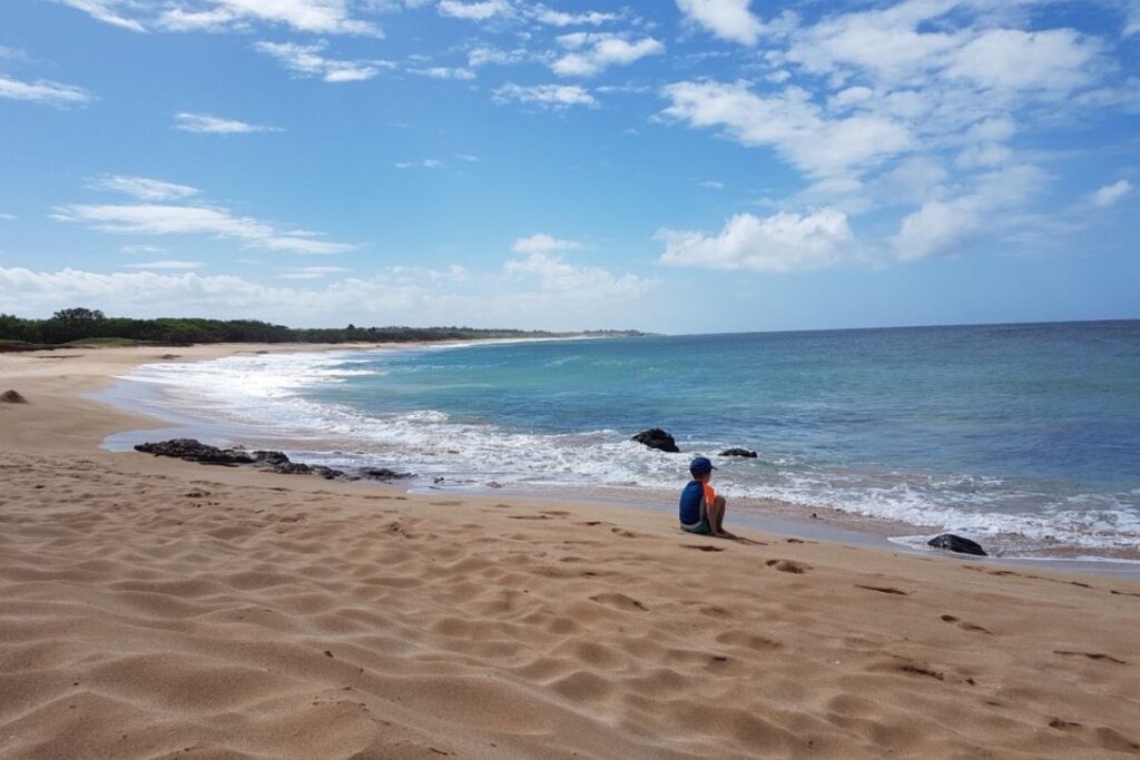 a child sits on a white sand beach