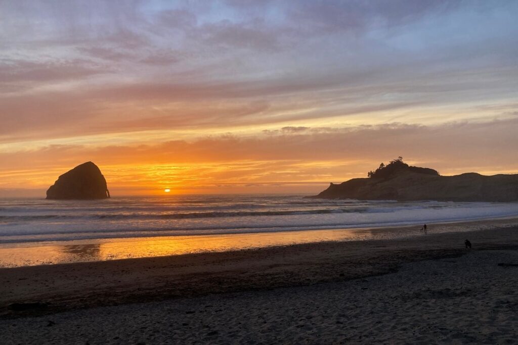 Sunset on a beach with rocks in the ocean
