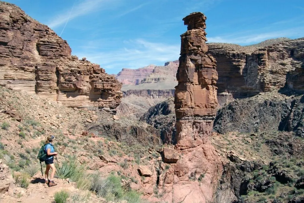 A hiker in the grand canyon looks at a rock formation
