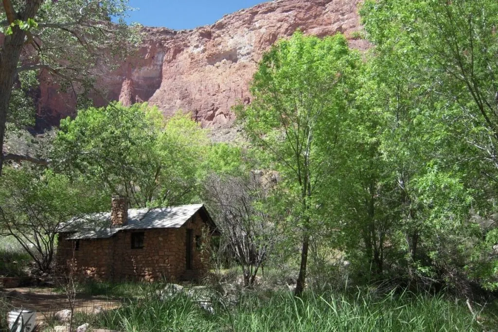A rock building in the trees with tall canyon walls.