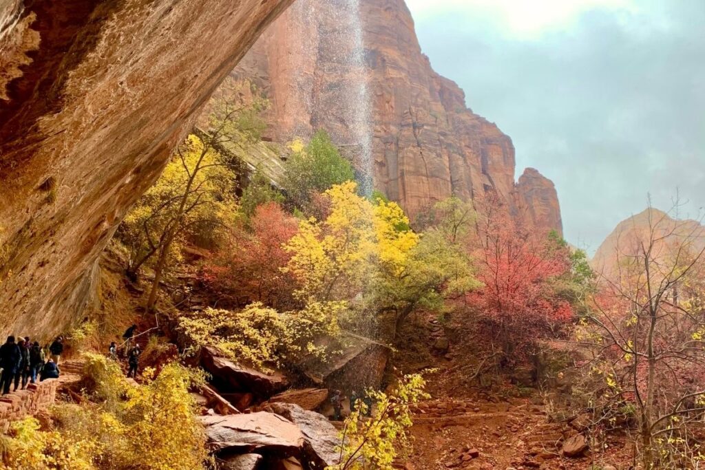 A trail pass under a waterfall coming off a cliff
