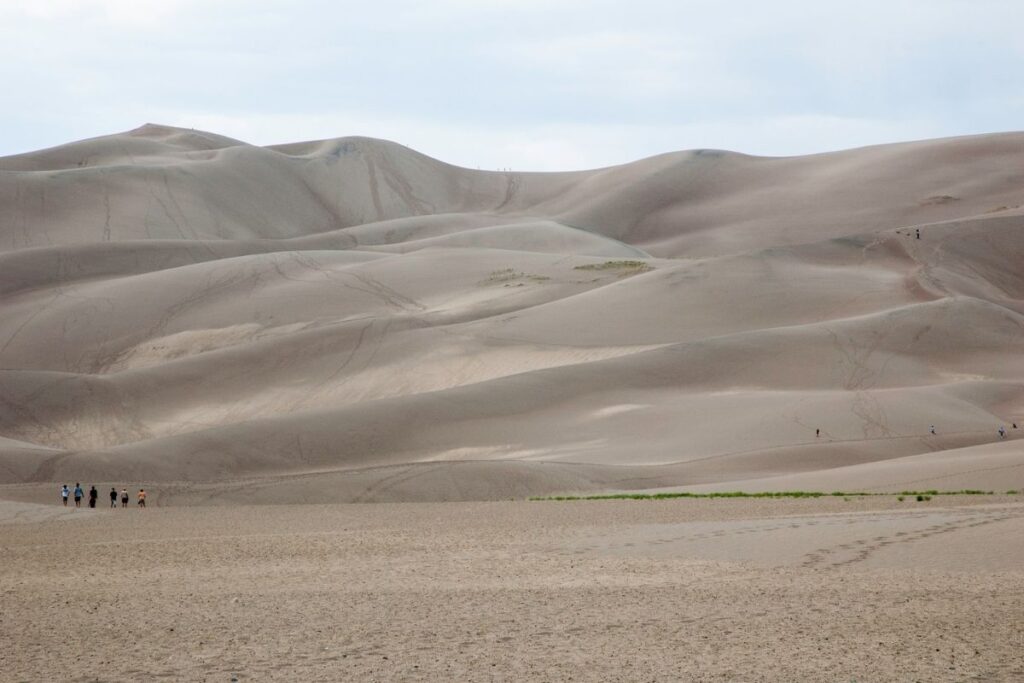 People walking up to a sand dune.