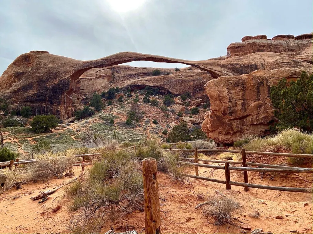 A long skinny arch with a rock wall behind it.