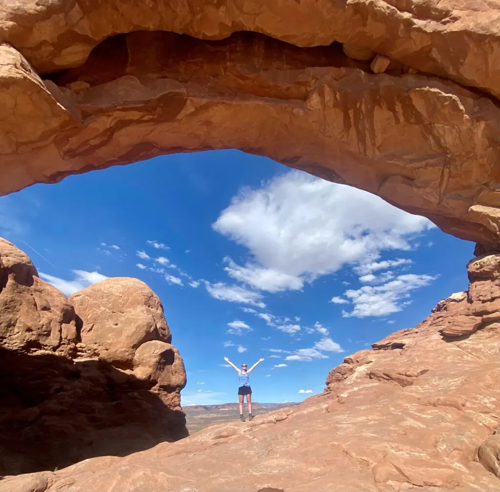 A women stands under a rock arch.  