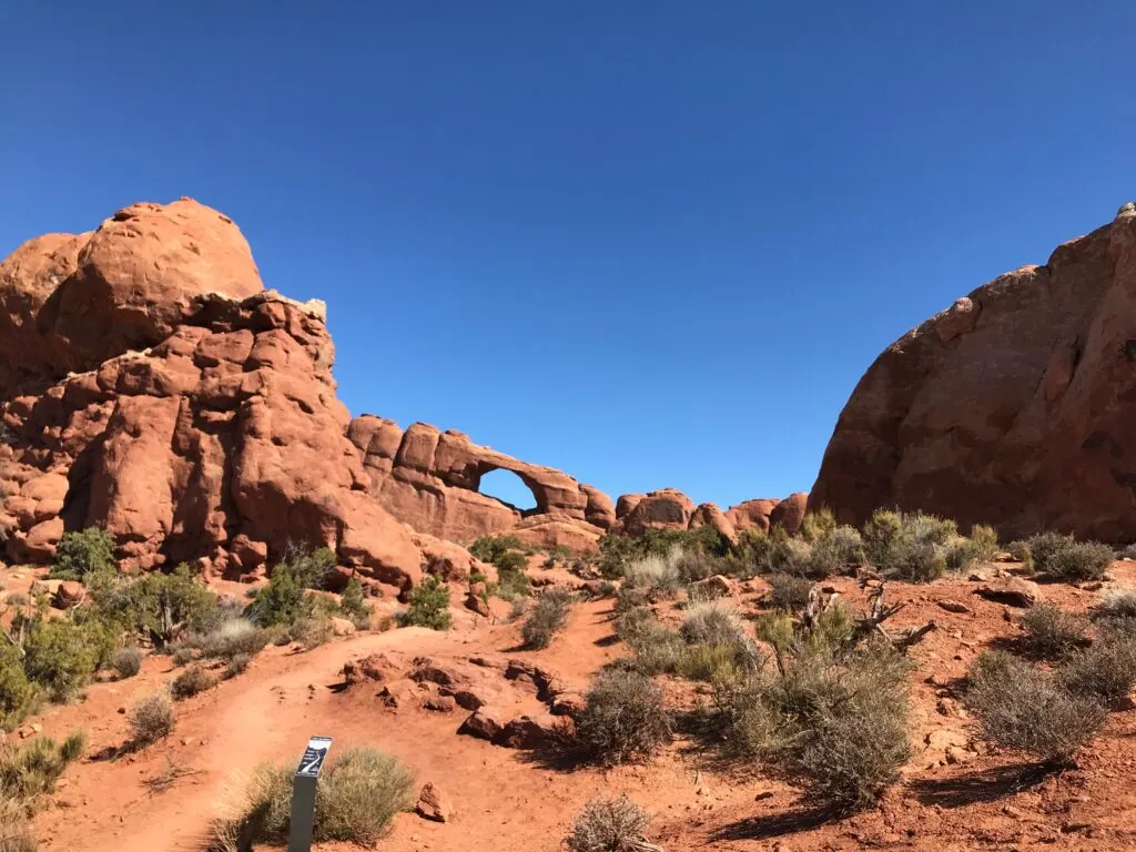 A rock wall with a arch in the middle of it.  