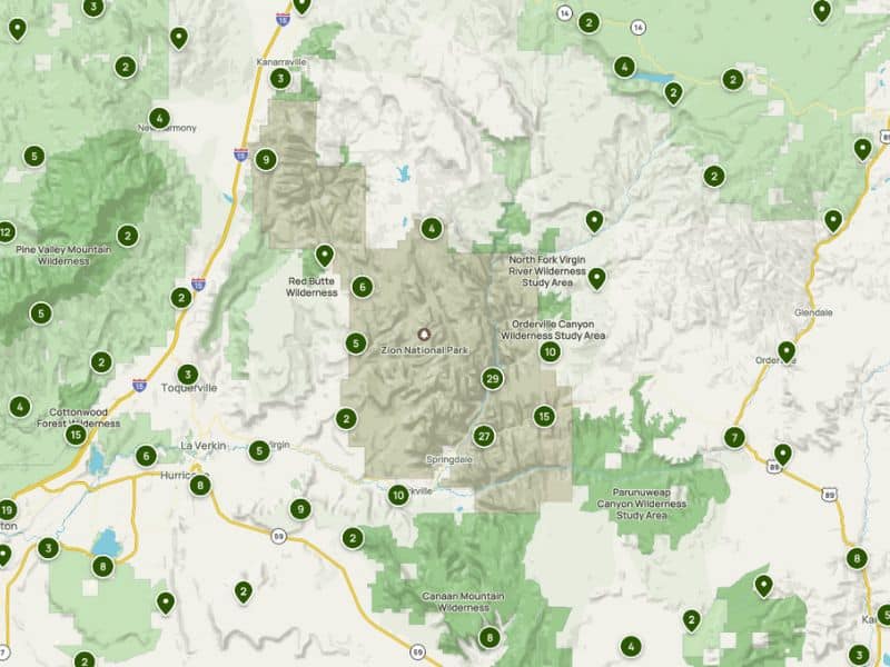 This image displays a map view centered around Zion National Park and its surrounding areas. It features various marked points indicating trails, landmarks, and wilderness areas, such as Pine Valley Mountain Wilderness and Red Butte Wilderness. Major routes and towns like Hurricane and Springdale are visible, and the terrain is differentiated by shades of green and gray to distinguish between mountainous regions and flatlands. Each marked point is labeled with a number, possibly representing specific trails or attractions within the park.