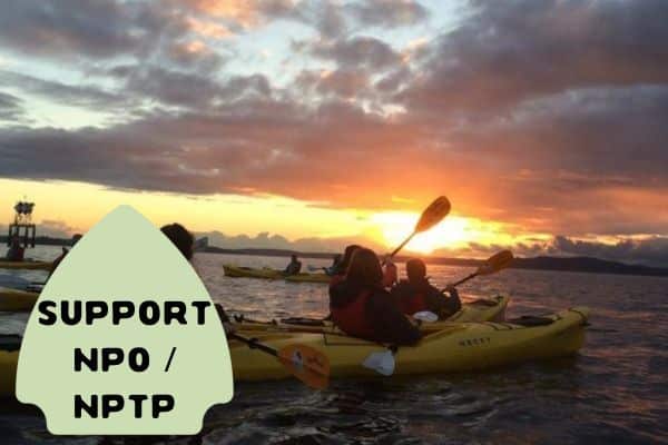 This image captures a group of kayakers in yellow boats paddling on calm waters during a stunning sunset. The sky is filled with dramatic clouds, and the horizon is painted with vibrant colors of the setting sun.