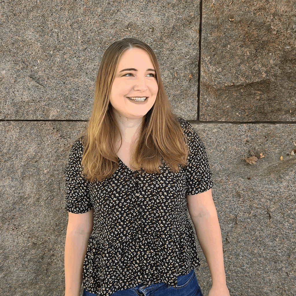 A white women standing in front a wall.